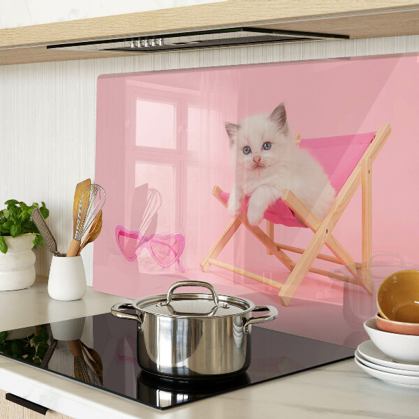 Tabla de cortar Un gatito en una tumbona sobre un fondo rosa.