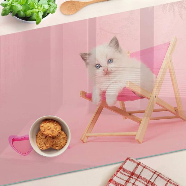 Tabla de cortar Un gatito en una tumbona sobre un fondo rosa.