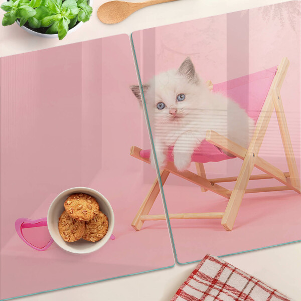 Tabla de cortar Un gatito en una tumbona sobre un fondo rosa.