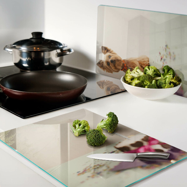 Tabla de cortar de cristal Un perro en la mesa con un pastel.