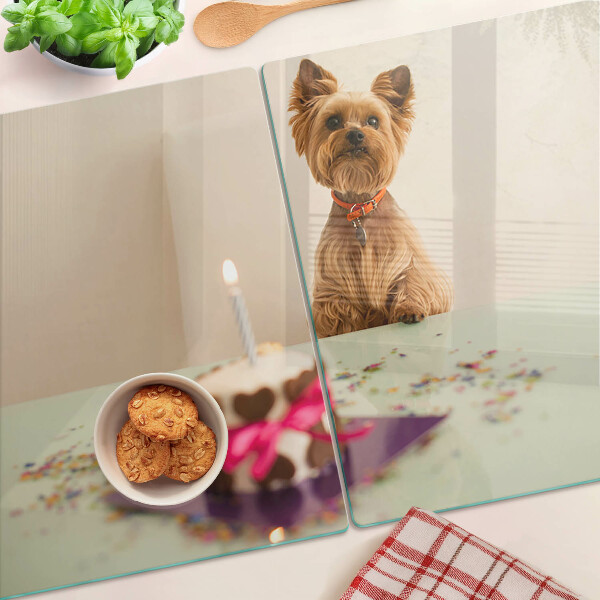 Tabla de cortar de cristal Un perro en la mesa con un pastel.