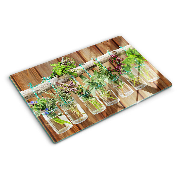 Tabla de cortar de cristal Hierbas en frascos sobre un fondo de madera.