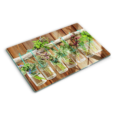 Tabla de cortar de cristal Hierbas en frascos sobre un fondo de madera.