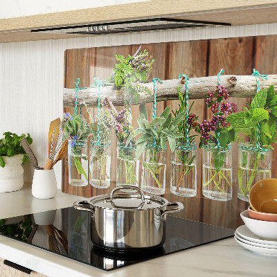 Tabla de cortar de cristal Hierbas en frascos sobre un fondo de madera.