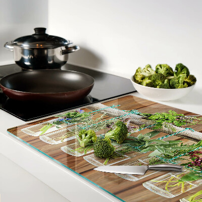 Tabla de cortar de cristal Hierbas en frascos sobre un fondo de madera.