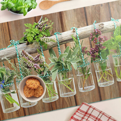 Tabla de cortar de cristal Hierbas en frascos sobre un fondo de madera.