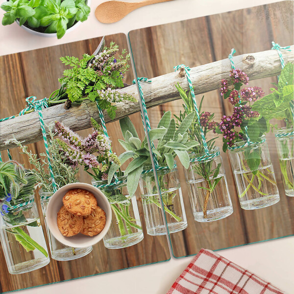 Tabla de cortar de cristal Hierbas en frascos sobre un fondo de madera.