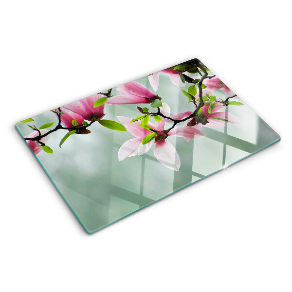 Tabla de cortar de cristal Flores de magnolia sobre un fondo verde.