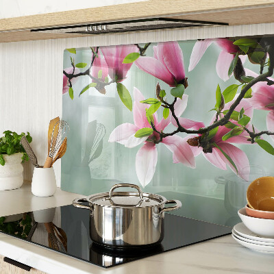 Tabla de cortar de cristal Flores de magnolia sobre un fondo verde.