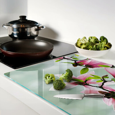 Tabla de cortar de cristal Flores de magnolia sobre un fondo verde.