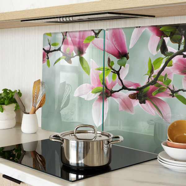 Tabla de cortar de cristal Flores de magnolia sobre un fondo verde.