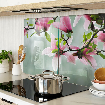Tabla de cortar de cristal Flores de magnolia sobre un fondo verde.