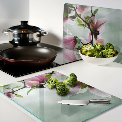 Tabla de cortar de cristal Flores de magnolia sobre un fondo verde.