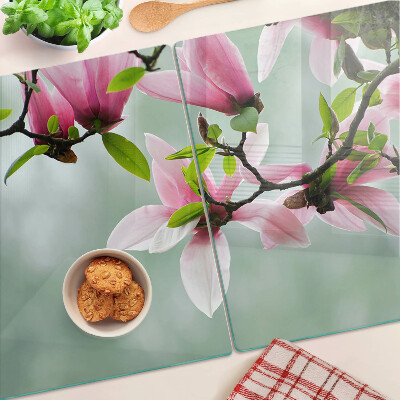 Tabla de cortar de cristal Flores de magnolia sobre un fondo verde.