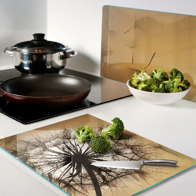 Tabla de cortar de cristal Dientes de león contra el fondo del atardecer