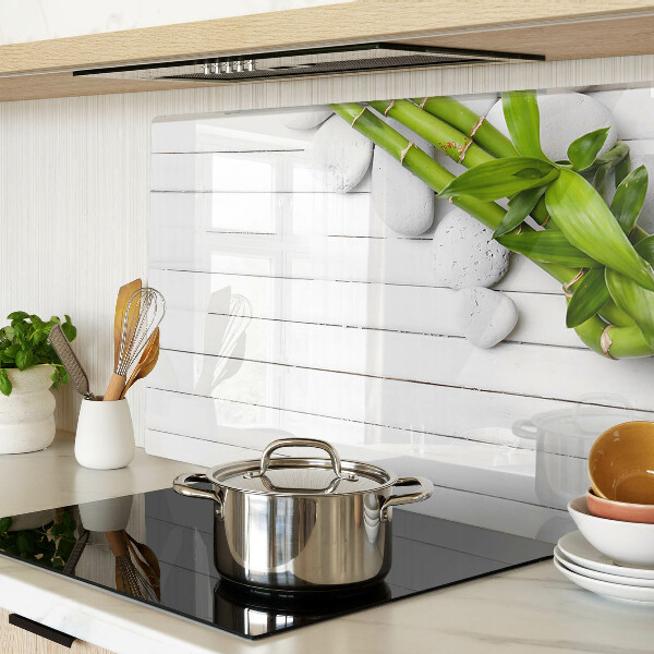 Tabla de cortar de cristal Bambú y piedras sobre un fondo de madera.