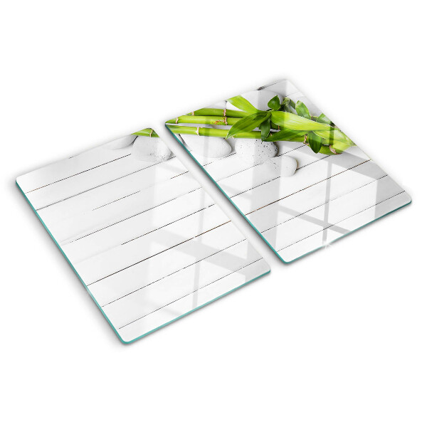 Tabla de cortar de cristal Bambú y piedras sobre un fondo de madera.