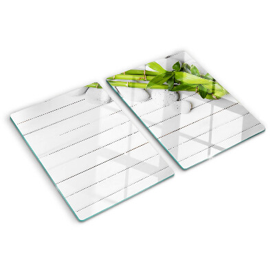 Tabla de cortar de cristal Bambú y piedras sobre un fondo de madera.