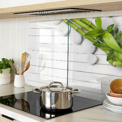 Tabla de cortar de cristal Bambú y piedras sobre un fondo de madera.