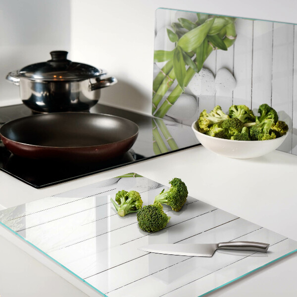 Tabla de cortar de cristal Bambú y piedras sobre un fondo de madera.