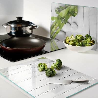 Tabla de cortar de cristal Bambú y piedras sobre un fondo de madera.