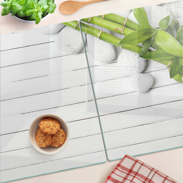 Tabla de cortar de cristal Bambú y piedras sobre un fondo de madera.