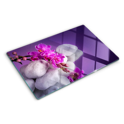 Tabla de cortar Flores de orquídea sobre un fondo de piedras.
