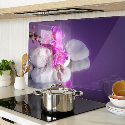 Tabla de cortar Flores de orquídea sobre un fondo de piedras.