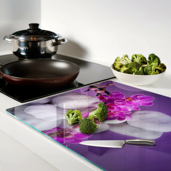 Tabla de cortar Flores de orquídea sobre un fondo de piedras.