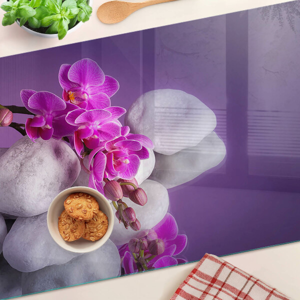 Tabla de cortar Flores de orquídea sobre un fondo de piedras.