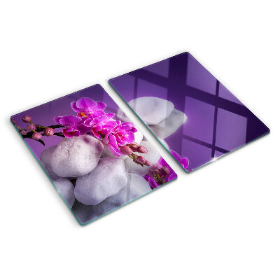 Tabla de cortar Flores de orquídea sobre un fondo de piedras.