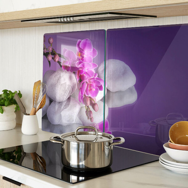 Tabla de cortar Flores de orquídea sobre un fondo de piedras.