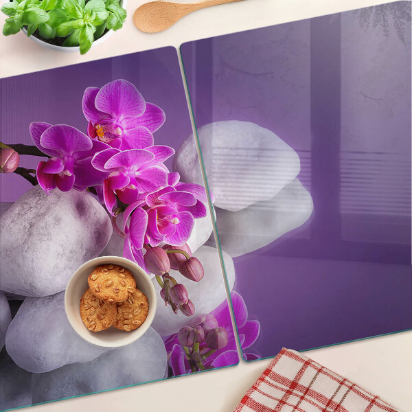 Tabla de cortar Flores de orquídea sobre un fondo de piedras.