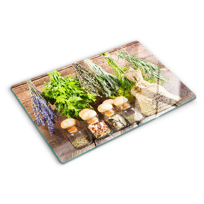 Tabla de cortar de cristal Hierbas y especias sobre un fondo de madera.