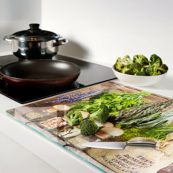 Tabla de cortar de cristal Hierbas y especias sobre un fondo de madera.