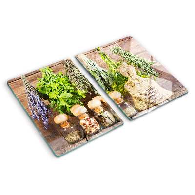 Tabla de cortar de cristal Hierbas y especias sobre un fondo de madera.