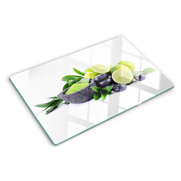 Tabla de cortar de cristal Limones y uvas sobre un fondo verde.