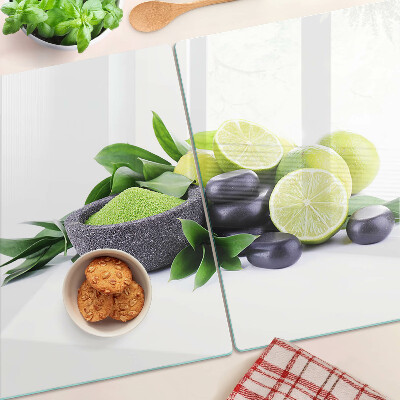 Tabla de cortar de cristal Limones y uvas sobre un fondo verde.