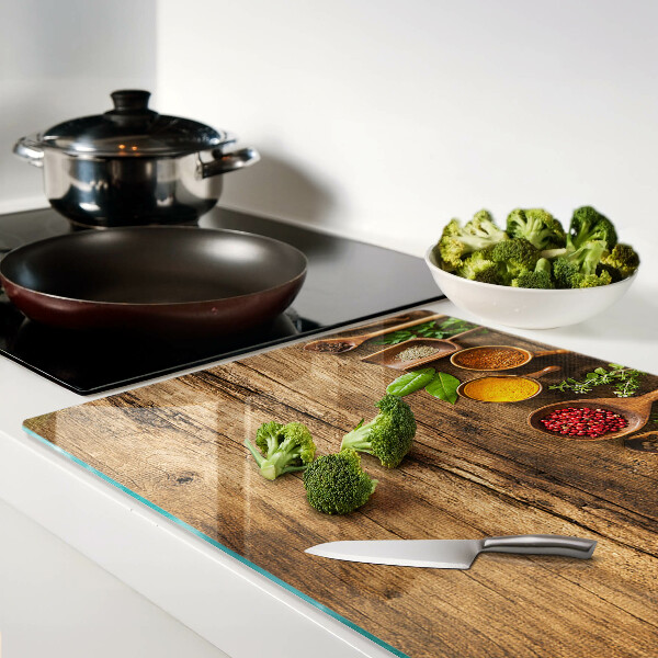 Tabla de cortar de cristal Especias y hierbas sobre un fondo de madera.