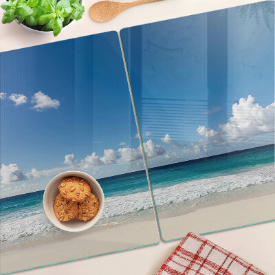 Tabla de cortar de cristal Una playa con agua turquesa y nubes.