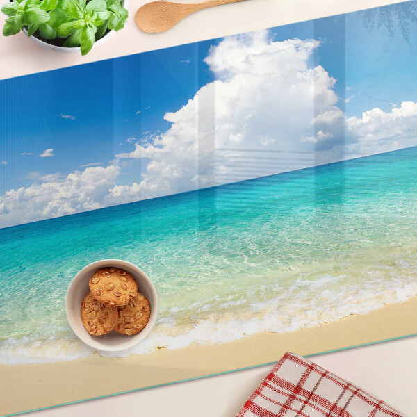 Tabla de cortar de cristal Una playa con agua turquesa y nubes.