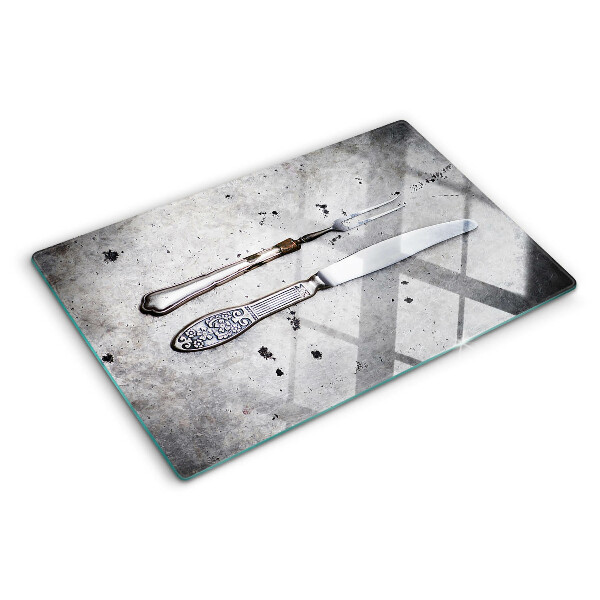 Tabla de cortar de cristal Cubiertos sobre un fondo de hormigón