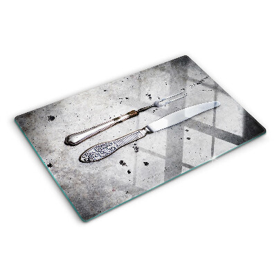 Tabla de cortar de cristal Cubiertos sobre un fondo de hormigón