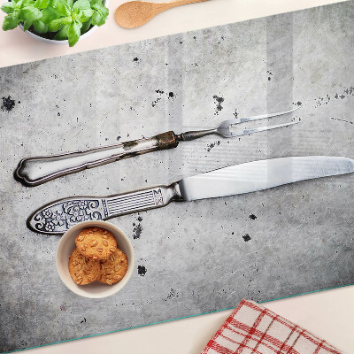 Tabla de cortar de cristal Cubiertos sobre un fondo de hormigón