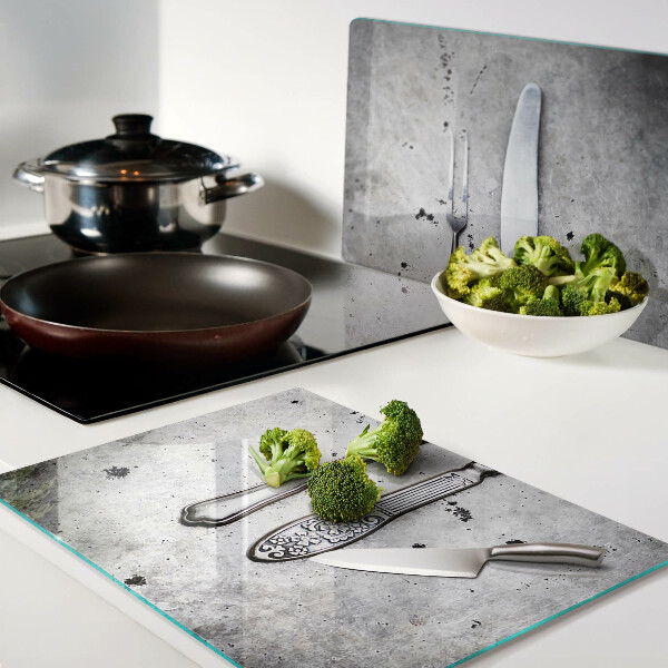 Tabla de cortar de cristal Cubiertos sobre un fondo de hormigón