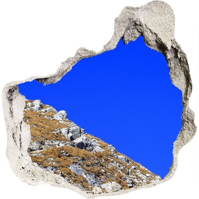 Vinilo decorativo boquete pared irregular Paisaje de montaña a través de un agujero en la pared.