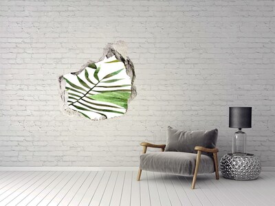 Vinilo decorativo boquete pared irregular Palmera verde a través de un agujero en la pared.