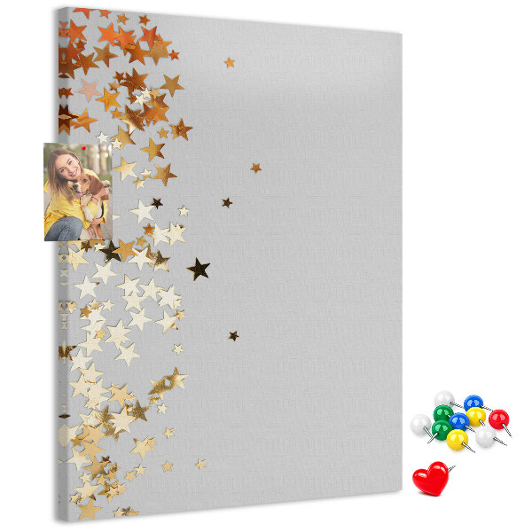 Tablón de corcho Estrellas doradas y plateadas sobre fondo gris.