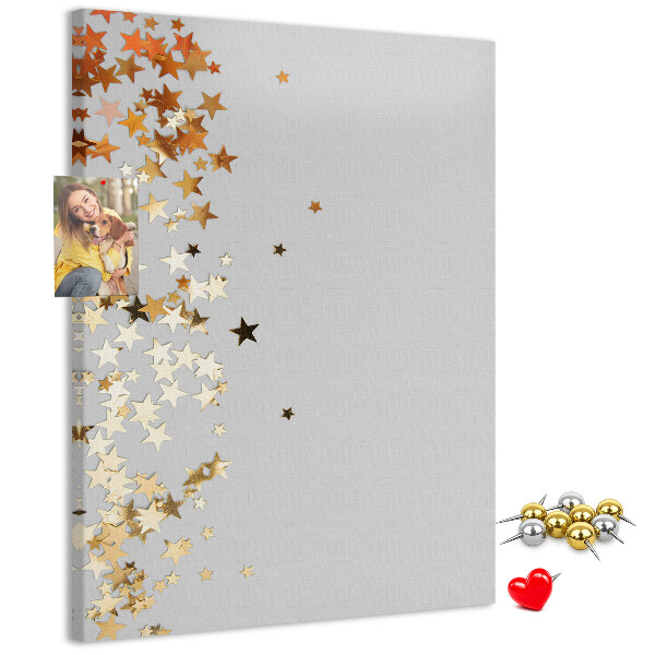 Tablón de corcho Estrellas doradas y plateadas sobre fondo gris.