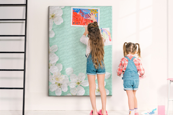 Pizarra de corcho decorativa con detalles florales sobre un fondo pastel